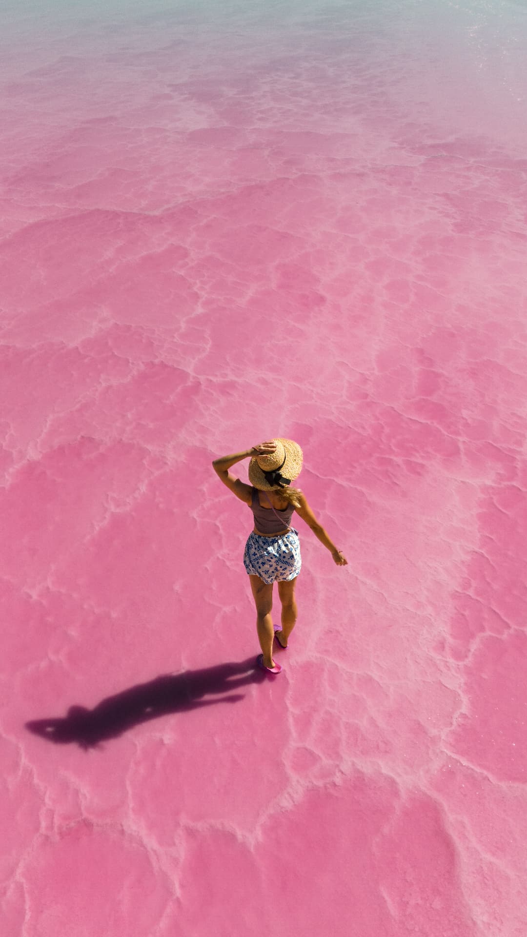 Person walking across a vivid pink salt lake