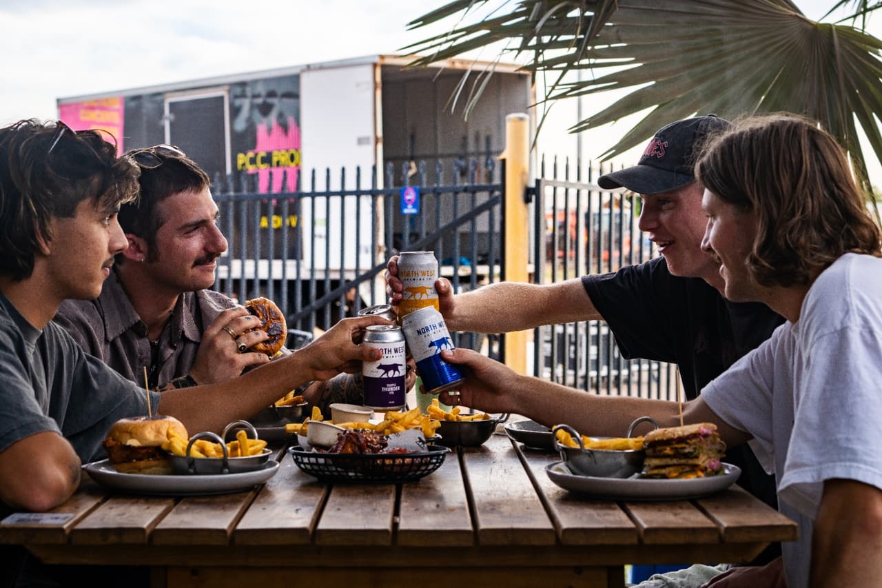 Friends cheering with cans over a shared meal